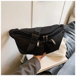 Close-up of black crossbody chest bag with triple zipper pockets and nylon strap