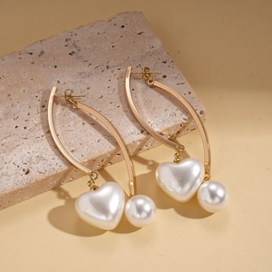 Boucles d'oreilles dorées avec perles en forme de cœur et rondes sur fond de pierre