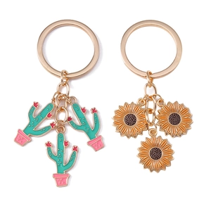 Golden metal keychains with pastoral sunflower and cactus enamel charms on white background