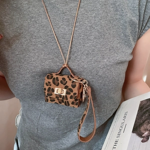 Detail of leopard print faux suede mini bag charm with golden metal clasp on model