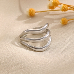 Détail de la bague argentée multicouche ondulée sur un fond de soie beige élégant