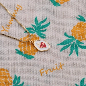 Collier géométrique doré minimaliste avec pendentif cœur rouge sur fond texturé