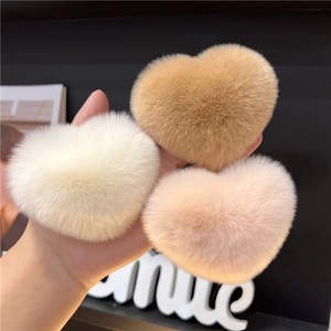 Close-up of heart-shaped plush hair clips in beige, white, and soft pink fur