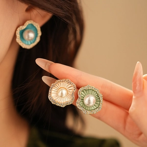 Détail de boucles d'oreilles perles dorées avec émail vert et zircons scintillants