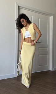 Two-piece pale yellow knit set featuring a buttoned vest and matching long midi skirt