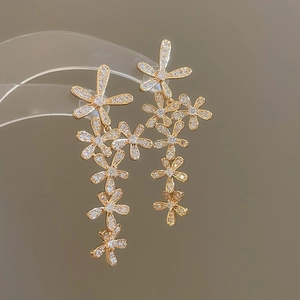 Macro detail of gold flower tassel earrings with zircons on a display stand