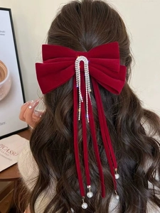 Dettaglio di fiocco in velluto rosso con nappe di strass e perle su capelli lunghi