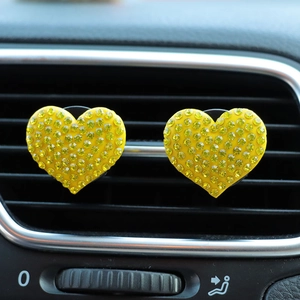 Detailed macro view of yellow rhinestone heart car vent clips on an air grille