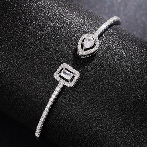 Macro shot of silver open cuff bracelet with emerald and teardrop cut zircon stones