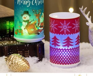 Detail of LED Christmas candles with Santa Claus and snowflake prints on textured surface