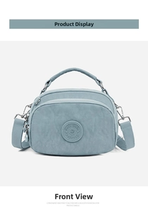 Front view of light blue multi-zipper crossbody bag with top handle and woven strap