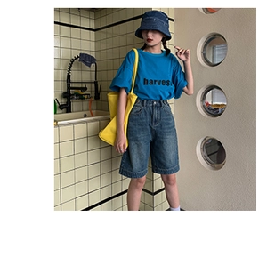Close-up of a large yellow canvas tote bag paired with a blue t-shirt and denim outfit