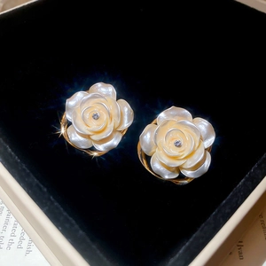 Vue macro de boucles d'oreilles rose blanche en résine avec diamants et écrin en velours