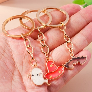 Detail of Halloween ghost, pumpkin hat and bat enamel keychains in gold metal