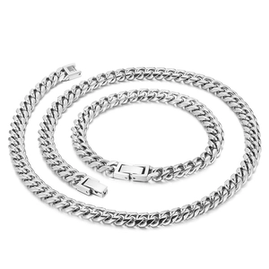 Polished silver stainless steel Cuban link necklace and bracelet set on white background