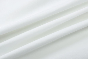 Gros plan sur la texture du tissu blanc et les plis doux de cette robe moulante chic