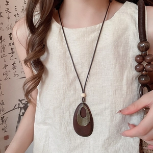 Close-up of vintage teardrop wood pendant and bronze metallic detail on sweater chain