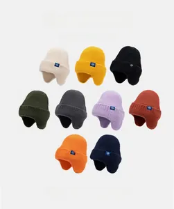 Détail de bonnets d'hiver en tricot avec cache-oreilles en neuf couleurs et logo flocon