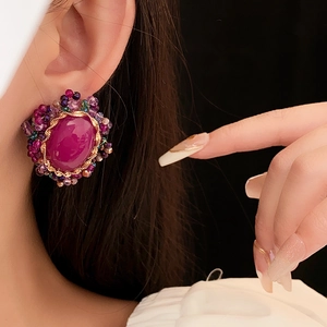 Close-up of vintage oval magenta gemstone earring with handcrafted bead embroidery