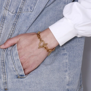 Detail of titanium steel gold heart OT clasp chain bracelet worn on denim jacket sleeve