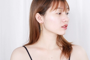 Close-up of golden vertical LOVE hollow letters on a long tassel chain earring