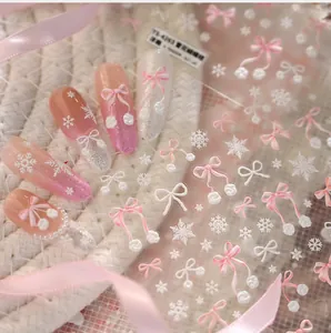 Macro view of 3D embossed pink bow and white snowflake nail stickers on gradient base