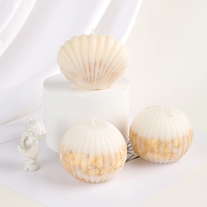 Detail of shell and ribbed sphere candles with gold foil accents on white silk