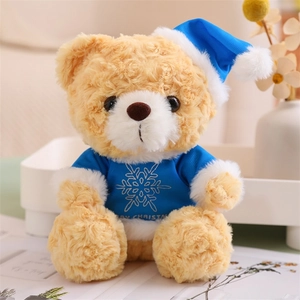 Close-up of beige teddy bear in blue Merry Christmas sweater and hat decoration