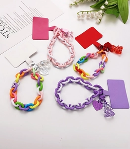 Close-up of colorful acrylic phone wrist straps with bear charms and metal heart tags