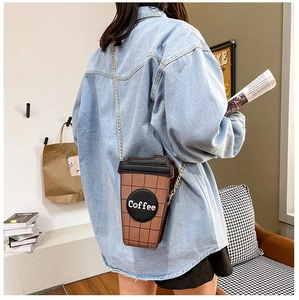 Fashionable coffee cup shaped crossbody bag with gold chain strap shown on a model