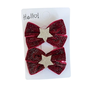 Pair of red velvet bow hair clips with gold glitter stars on a white display card