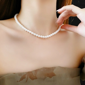 Gros plan d'un collier ras de cou en perles blanches porté par un mannequin élégant