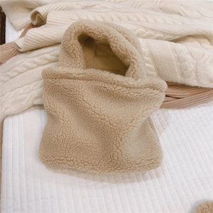 Gros plan du petit sac à main en laine d'agneau beige sur un pull en maille confortable