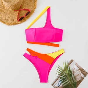 Dettaglio flat lay del bikini monospalla color-block con motivi geometrici neon vivaci
