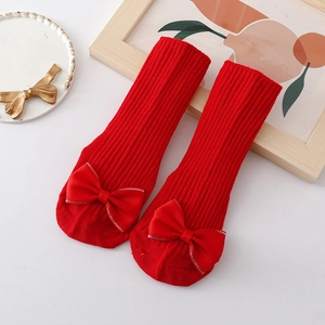Detail of red cable knit baby floor socks with decorative bow and non-slip bottom