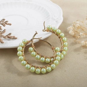 Detail of gold hoop earrings with handmade mint green mother-of-pearl bead wrapping