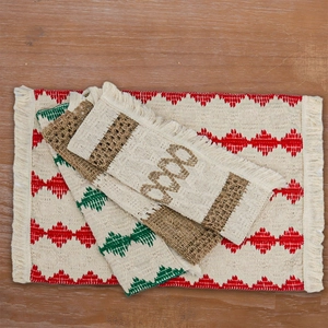 Close-up of geometric woven placemats with tassels in red, green, and brown on wood