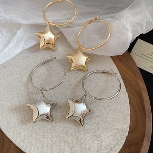 Dettaglio di orecchini a cerchio con ciondolo a stella in finitura oro e argento
