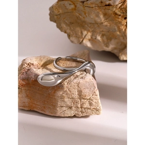 Detail of silver water-drop irregular open ring placed on natural stone surface