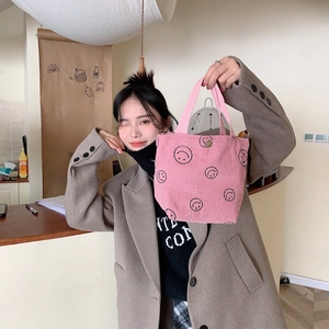 Detailed close-up of pink corduroy tote bag with a minimalist black smiley face print