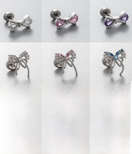 Macro shot of titanium steel bow piercings with sparkling zircon inlays and flat disc bases