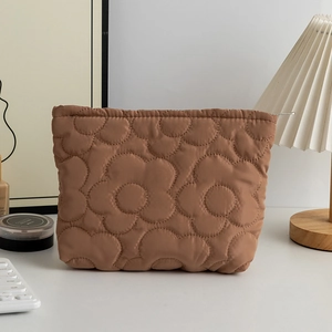 Dettaglio della borsa cosmetica marrone con trapuntatura floreale su una scrivania