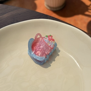 Detailed macro view of cupcake-shaped acrylic hair claw clip in a porcelain bowl