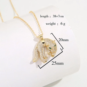 Detail of 18K gold plated leopard pendant with clear crystals and green eyes on a white stand