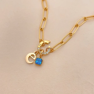 Detail van 14K vergulde titanium ketting met letter e en blauwe edelsteen hanger