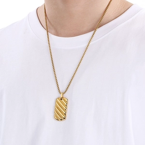 Detail of 18K gold stainless steel pendant with textured stripes on a male model
