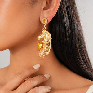Detail of vintage gold horse head drop earring with yellow crystals on female model