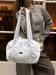 Detail einer weichen Plüschhandtasche in Blau und Weiß mit metallischem Sozakka-Logo