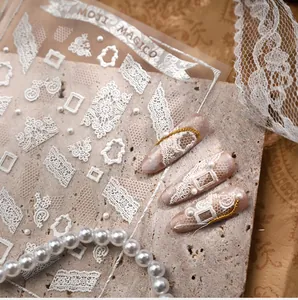 Macro detail of white 3D embossed lace nail stickers with elegant pearl accents