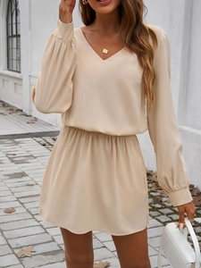 Détail d'une robe beige élégante à col en V avec manches bouffantes et taille cintrée